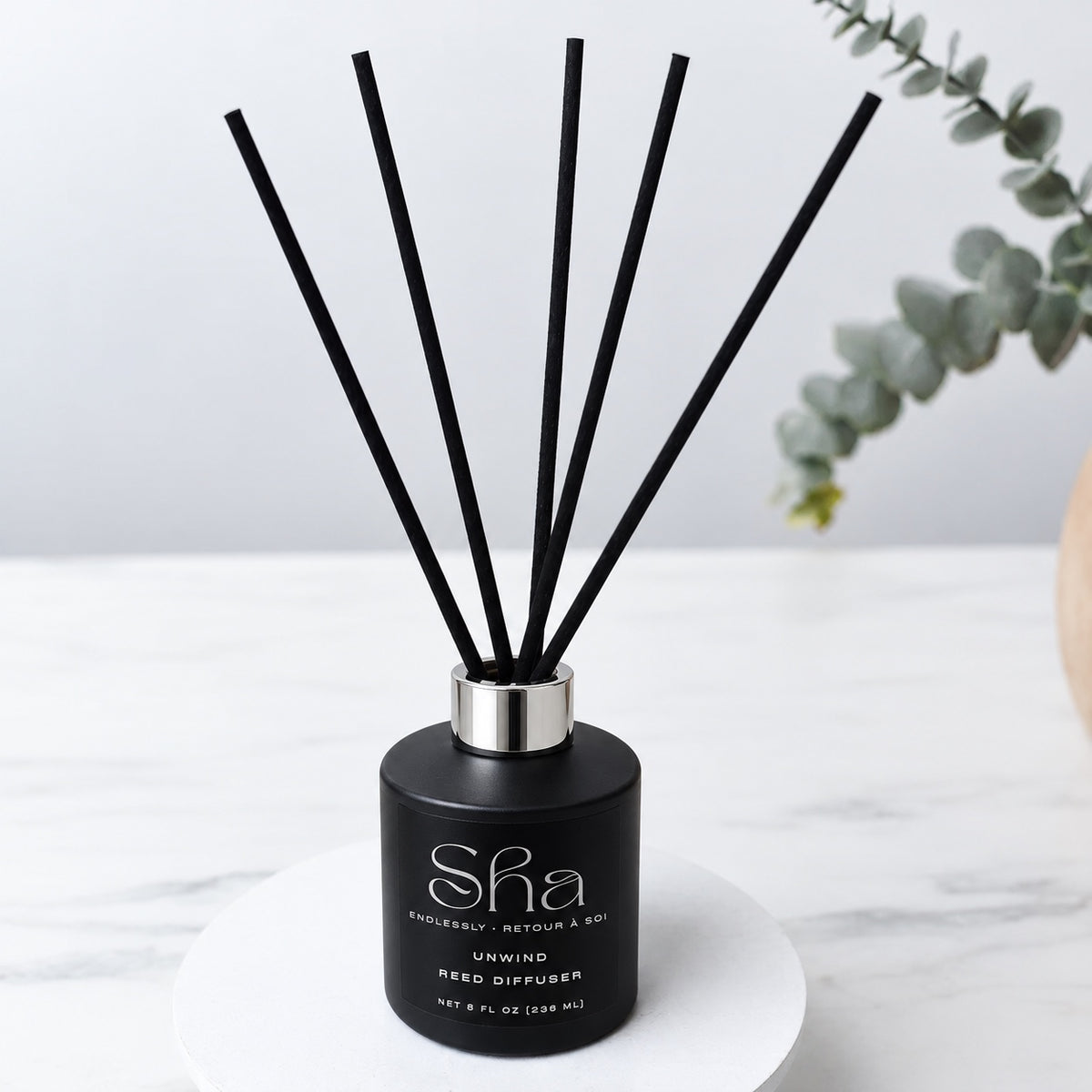 SHA Unwind reed diffuser with black reeds in a black bottle